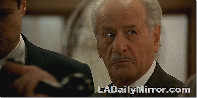 Man with mustache in coat and cowboy hat. 