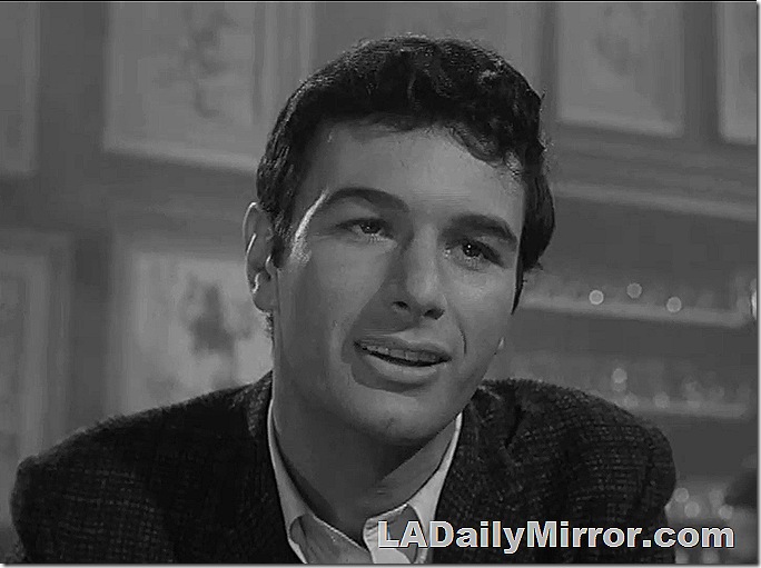 Man with dark hair, suit coat with open-collared shirt. 