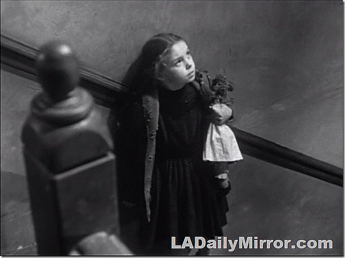 Girl standing on stairway, holding a doll. 