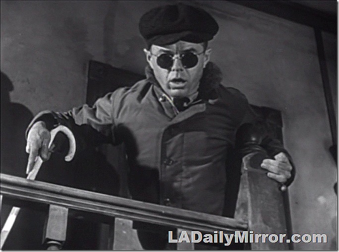 Mysterious man wearing a newsboy cap and sunglasses, and carrying a cane. 