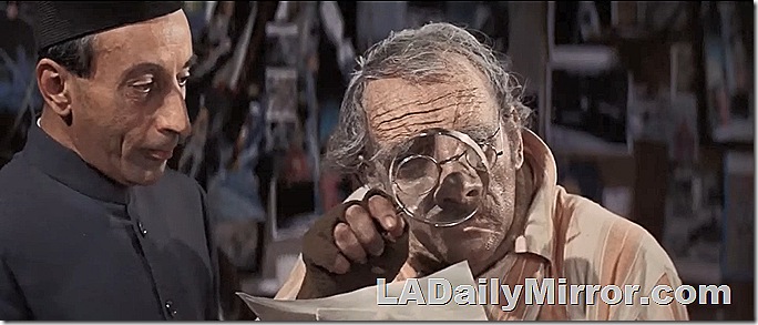 Man looking through magnifying glass. A second man observes. 