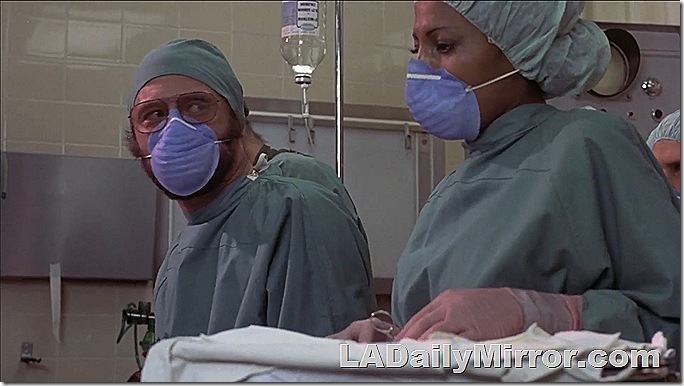 Surgical team in green scrubs, wearing masks. 