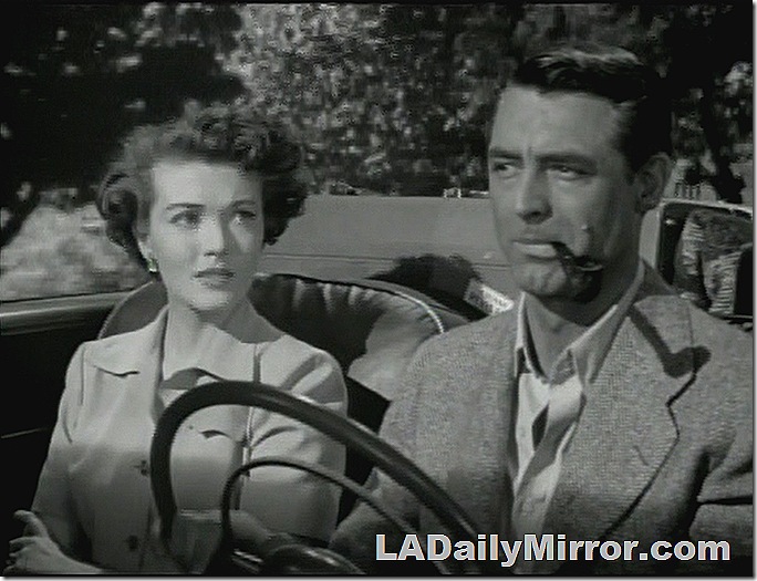 Man in coat with open collar, smoking a pipe and driving a car. A woman is sitting beside him. Man in coat with open collar, smoking a pipe and driving a car. A woman is sitting beside him.