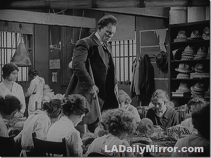 Man on crutches, on a table surrounded by women making hats. Man on crutches, on a table surrounded by women making hats.