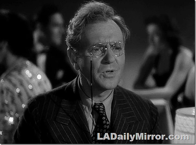 Man with disheveled hair, wearing a pinstripe suit and pince-nez glasses. 
