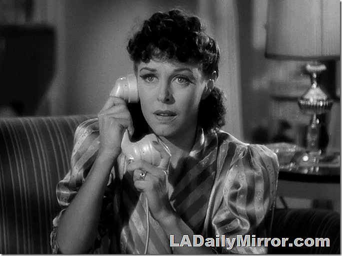 Woman in striped top with long hair pulled back talking on the phone 