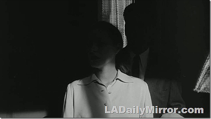 Man and woman standing at a doorway in the shadows. 