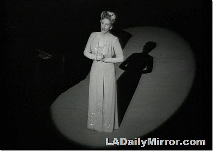 Woman on stage in floor-length gown, singing. Woman on stage in floor-length gown, singing.