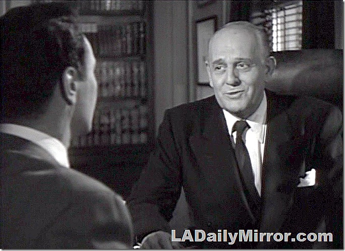 Man in coat and tie sitting at desk, talking to Back of the Head Guy. Man in coat and tie sitting at desk, talking to Back of the Head Guy.
