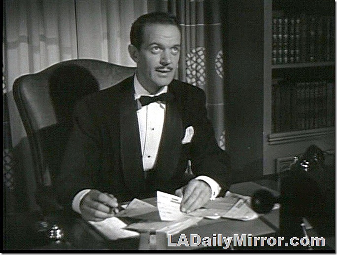 Man with mustache in tuxedo and bow tie sitting at desk. Man with mustache in tuxedo and bow tie sitting at desk.
