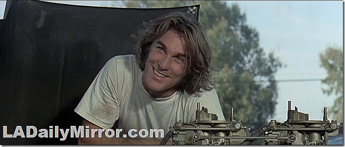 Man with long hair looking at engine compartment of a mysterious car. Man with long hair looking at engine compartment of a mysterious car.