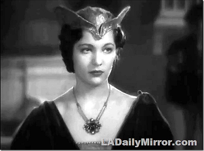 Woman with necklace and elaborate hat of a certain era. 