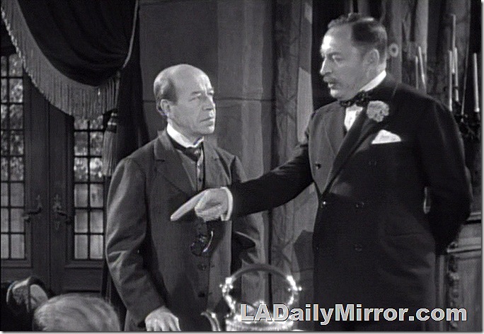 Man pointing at a body as another man watches. 