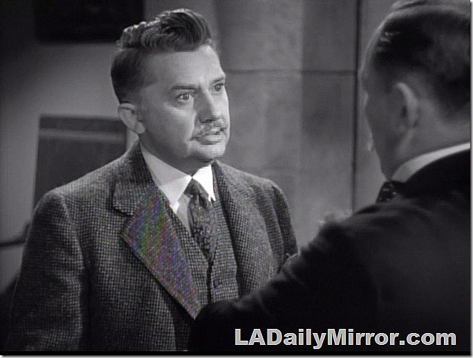 Man in three-piece suit and small mustache talking to Back of the Head Guy. 