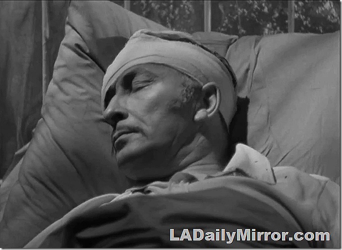 Man with bandaged head lying in bed. 