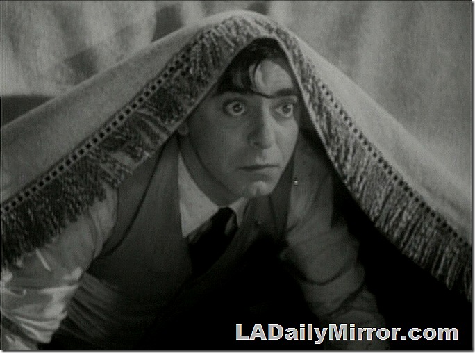Man peering out from under a tablecloth. 