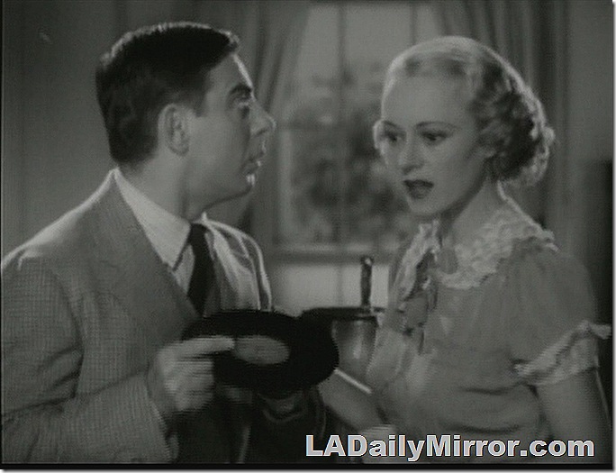 Woman looking at a phonograph record held by a man. 