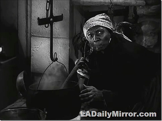 Woman wearing bandana stirring something in a pot hanging over a fire. Woman wearing bandana stirring something in a pot hanging over a fire.