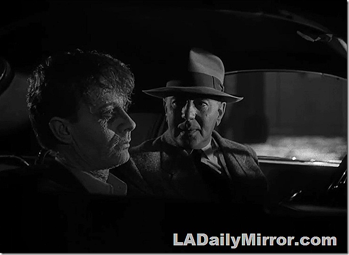 Two men sitting in a car. One is wearing a hat. The other is a zombie, who don't wear hats. 
